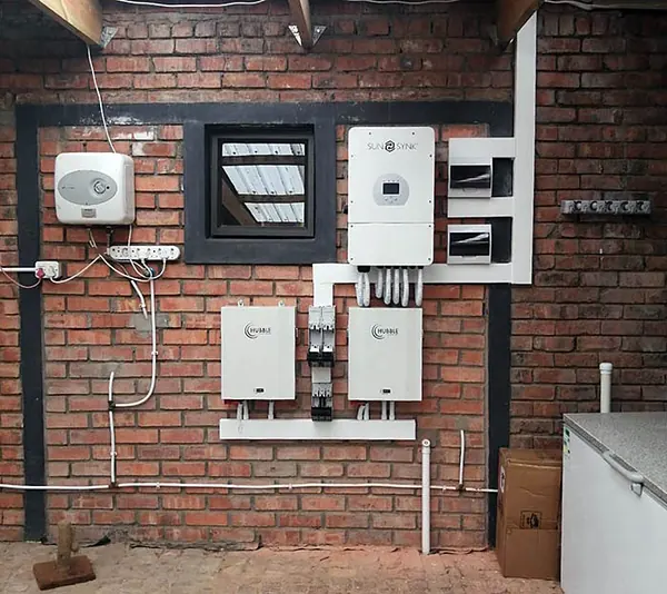 A hybrid inverter and two batteries mounted on a face-brick wall