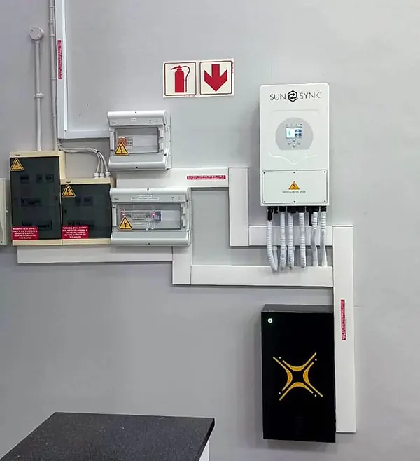 A Sunsynk hybrid inverter, battery and DB installed on a white wall with neat trunking
