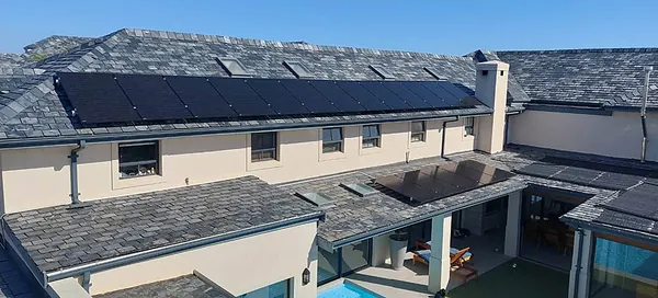 A family home with a row of black panels on a slate roof