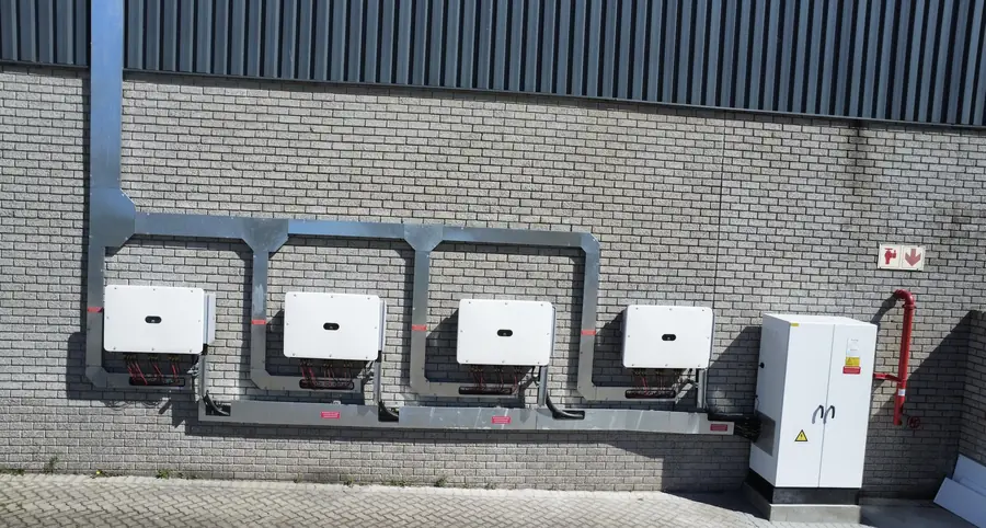 Four string inverters on an exterior wall framed by galvanised trunking